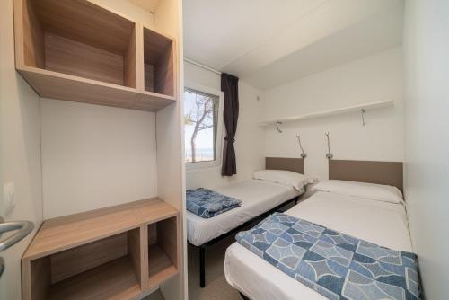a small bedroom with two beds and a window at Camping&Village Le Cernie in Lotzorai