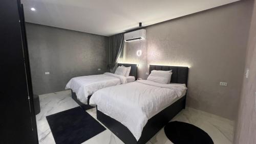 two beds in a hotel room with white sheets at كورنيش نيل معادي in Al Ma‘şarah