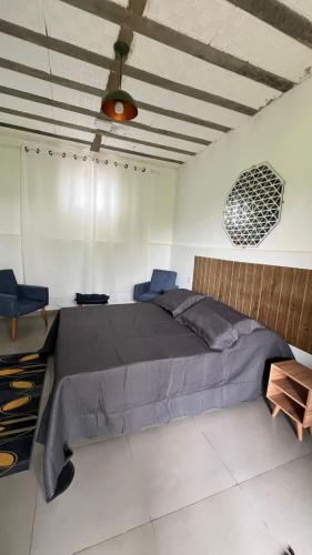 a bedroom with a large bed and two blue chairs at Complexo Luquinha in Delfinópolis