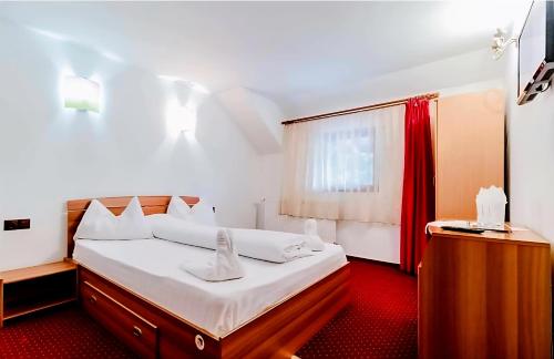 a bedroom with a bed with white sheets and a window at Pensiunea Vacanta in Lupeni