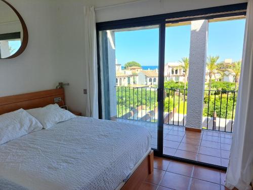 a bedroom with a bed and a balcony with a view at Les Oliveres Beach in Perelló
