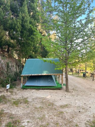 a tent with a blue roof next to a tree at Ermida Gerês Camping in Ermida