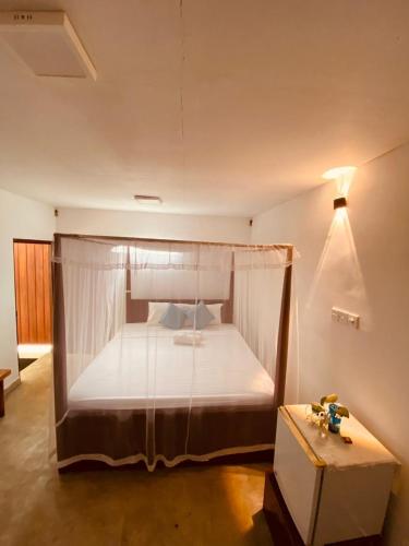 a bedroom with a bed with a canopy and a table at Lagoon Home Stay in Ahangama