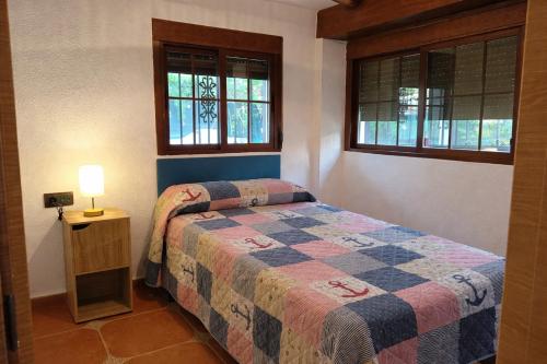 a bedroom with a bed and two windows at Villas con piscina en Punta Umbría by Villamya in Punta Umbría