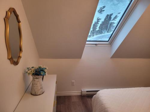 a bedroom with a window and a vase with flowers at Le Chalet du Domaine Gourmand in Thetford Mines