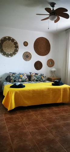 a bedroom with a yellow bed with a ceiling fan at Villa Gozo Holiday house in Teguitar