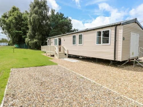 a caravan parked in a yard with a gravel driveway at Paws & Paths: A 3-Bedroom Retreat in Fritton in Belton