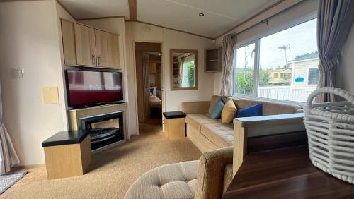 a living room with a couch and a television at Burgh Castle 3-Bed Haven: Near Norfolk Broads in Belton