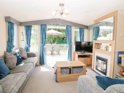 a living room with a couch and a tv at Paws & Paths: A 3-Bedroom Retreat in Fritton in Belton