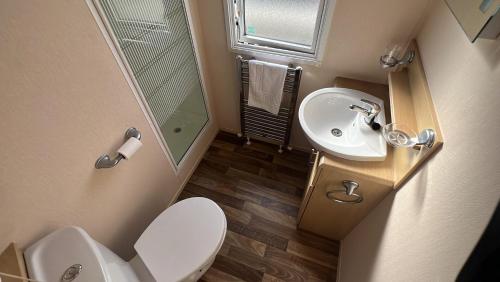 a small bathroom with a toilet and a sink at Burgh Castle 3-Bed Haven: Near Norfolk Broads in Belton