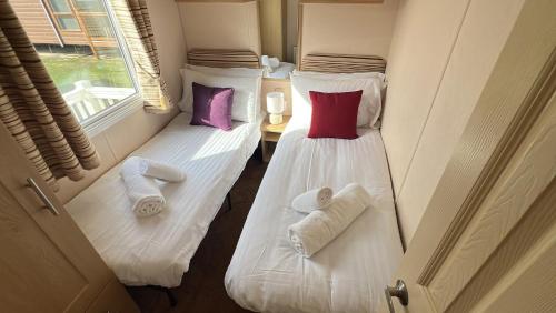 two beds in a room with towels and pillows at Burgh Castle 3-Bed Haven: Near Norfolk Broads in Belton