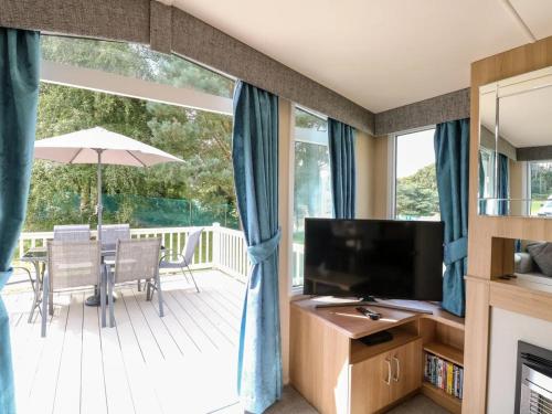 a living room with a television and a deck at Paws & Paths: A 3-Bedroom Retreat in Fritton in Belton