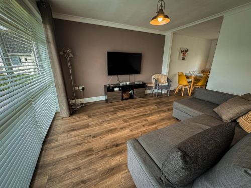 a living room with a couch and a flat screen tv at Dog Friendly Kessingland Chalet | Coastal Retreat in Kessingland