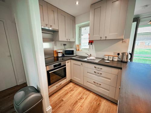 a kitchen with white cabinets and black counter tops at Dog Friendly Kessingland Chalet | Coastal Retreat in Kessingland