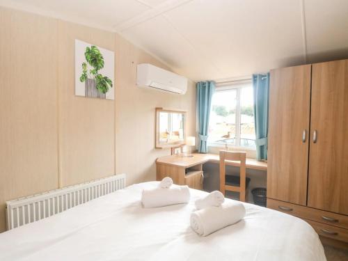 a bedroom with a bed with two towels on it at Paws & Paths: A 3-Bedroom Retreat in Fritton in Belton