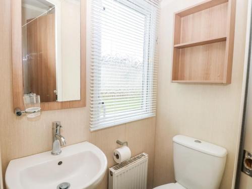 a bathroom with a sink and a toilet and a window at Paws & Paths: A 3-Bedroom Retreat in Fritton in Belton