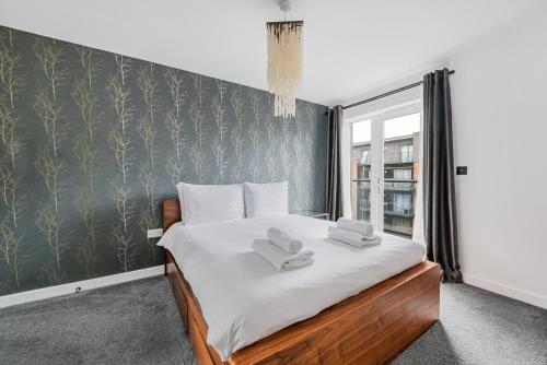 a bedroom with a large bed with two towels on it at Stylish Flat next2 Wimbledon with a parking in Mitcham Junction