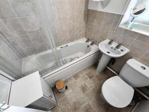 a bathroom with a tub and a toilet and a sink at Dog Friendly Kessingland Chalet | Coastal Retreat in Kessingland