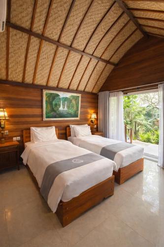 a bedroom with two beds and a large window at Putra Bali Villa by Antara in Klungkung
