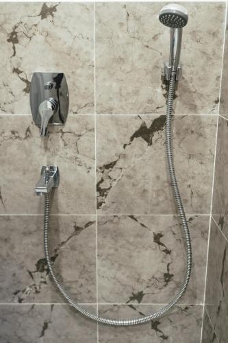a shower with a hose attached to a stone wall at The Southside Den in Āīzawl