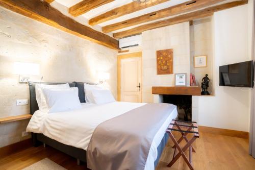 a bedroom with a white bed and a tv at L'Hostellerie de La Licorne in Fontevraud-l'Abbaye