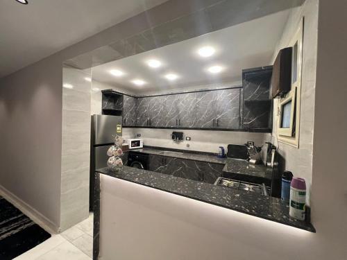 a kitchen with a black counter top and a refrigerator at كورنيش نيل معادي in Al Ma‘şarah