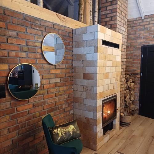 a brick fireplace with a mirror and a chair at Zacisze Częstkowo in Częstkowo