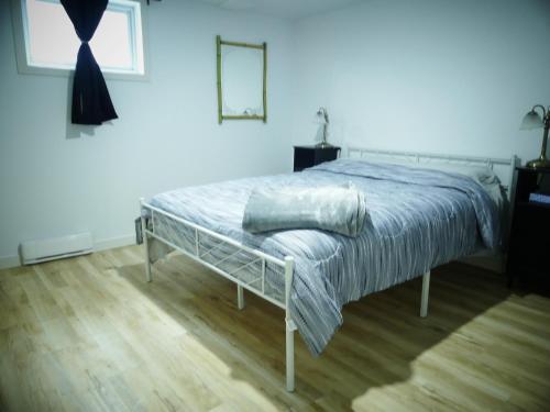 Ein Bett in einem weißen Schlafzimmer mit Holzboden in der Unterkunft Chambre privée dans logement partagé in Saint-Nazaire