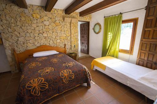 a bedroom with two beds and a stone wall at Catalunya Casas An oasis for up to 26 nature loving guests! in Sils