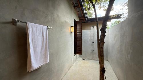 a bathroom with a shower and a white towel at Three Tree Villa By Habarana in Habarana