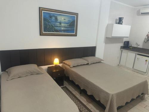 a room with two beds and a picture on the wall at Kitnet no interior de São Paulo 25 in Serra Negra