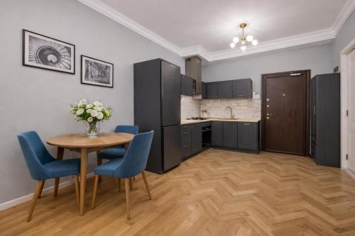 a kitchen with a wooden table and blue chairs at City Heart Apartment in Tbilisi City