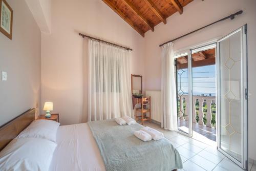 a bedroom with a bed and a large window at Villa Amalia By Elayan Villas Corfu in Karousádes