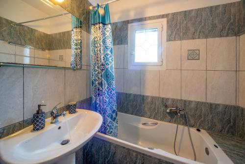 a bathroom with a sink and a tub and a mirror at Villa Amalia By Elayan Villas Corfu in Karousádes