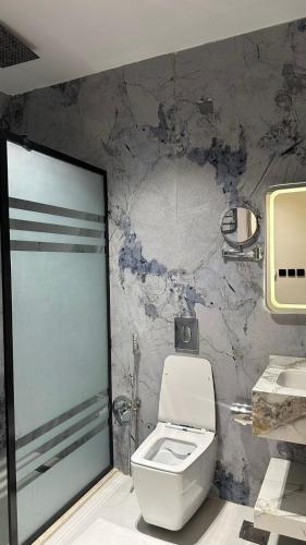 a bathroom with a white toilet and a marble wall at Al Seef Hotel in Al-ʿUla