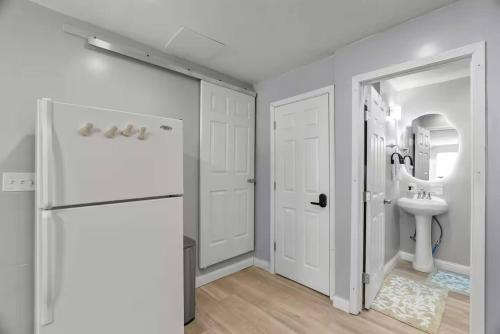 a white bathroom with a sink and a refrigerator at Boutique Studio Hideaway Near Forest Park in Saint Louis