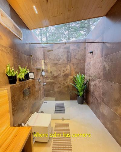a bathroom with a shower with potted plants in it at The GlampView Resort in Manāli