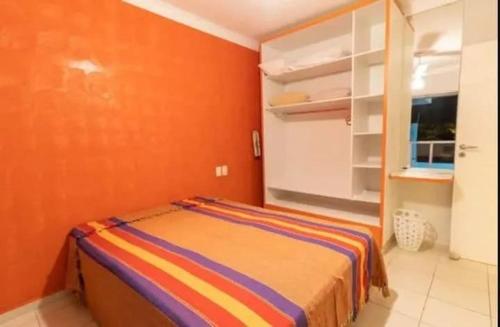 a bedroom with a bed with an orange wall at Casa de temporada com piscina in Peruíbe