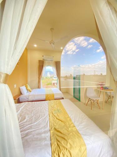 two beds in a room with a large window at LANBA Homestay in Phan Rang–Tháp Chàm