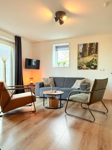 a living room with a blue couch and chairs at In de Zeeuwse Schuur in Biggekerke