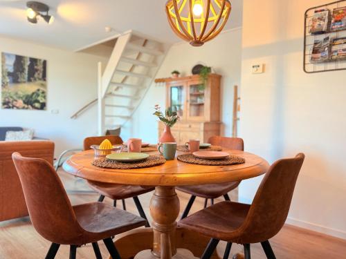 a dining room with a wooden table and chairs at In de Zeeuwse Schuur in Biggekerke