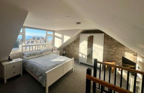 a bedroom with a bed and a staircase at Dog Friendly Cosy Coastal Cottage with Sea Views in Portland