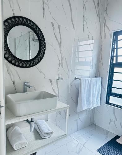 a white bathroom with a sink and a mirror at Sweet Daisies Apartment in Mbabane