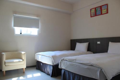 a bedroom with two beds and a chair and a window at Sunnyside Hotel in Kaohsiung