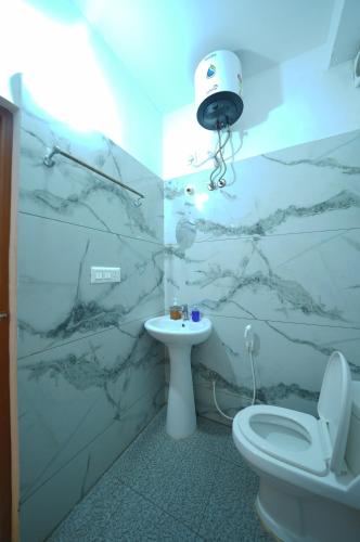 a bathroom with a white toilet and a sink at Cozy retreat in Mysore