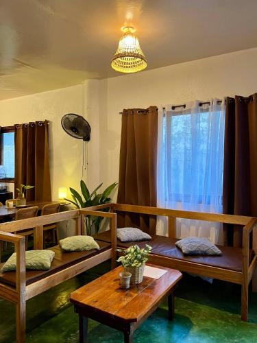 a living room with benches and a table and a chandelier at Paians 2BR Home, across Cloud 9, General Luna in Catangnan