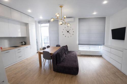 a kitchen and dining room with a table and a clock at ApartPlus - Затишні апартаменти in Dnipro