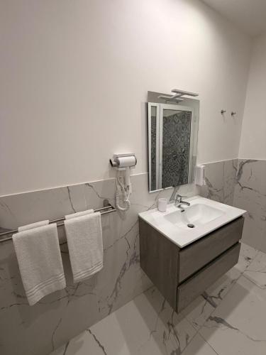 a white bathroom with a sink and a mirror at Vulcano Rooms 3 in Catania