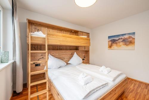 a bedroom with a wooden bunk bed with white sheets at Mountain Soulscape by myNests in Ennsling