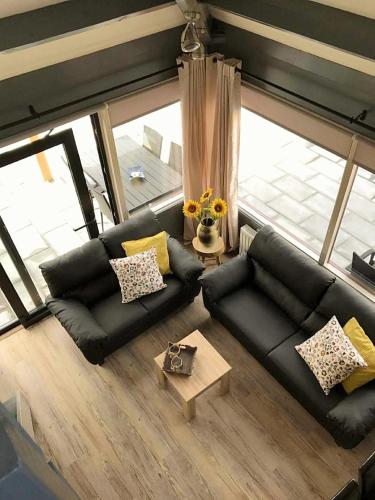 a living room with a black couch and a window at Zeeuwse Luwte in Stavenisse